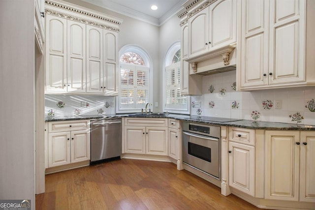 1418 Brighton Pl, Loganville, GA 30052 - kitchen with appliances with stainless steel finishes, cream cabinetry, crown molding, a sink, and wood finished floors