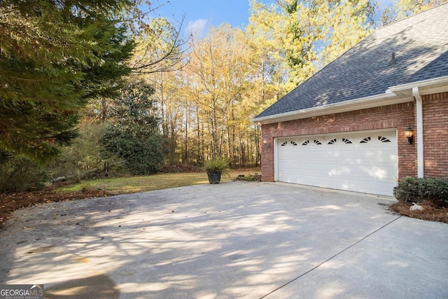 1418 Brighton Pl, Loganville, GA 30052 - view of side of home with brick siding, a shingled roof, concrete driveway, and an attached garage