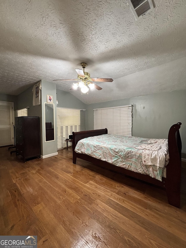 2220 Wellington Cir, Lithonia, GA 30058 - bedroom featuring visible vents, a textured ceiling, vaulted ceiling, and wood finished floors