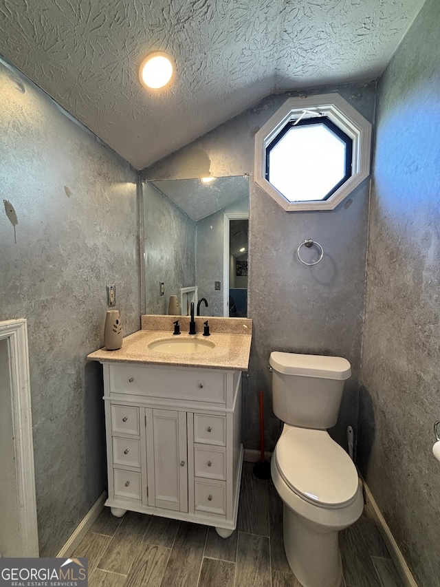 2220 Wellington Cir, Lithonia, GA 30058 - bathroom featuring vanity, baseboards, vaulted ceiling, wood finish floors, and toilet