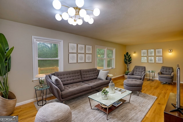 living room with light wood-style floors, an inviting chandelier, and baseboards