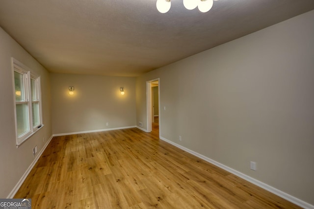 spare room featuring baseboards and light wood finished floors