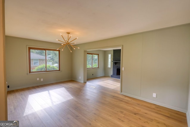 spare room with plenty of natural light, light wood-type flooring, and an inviting chandelier