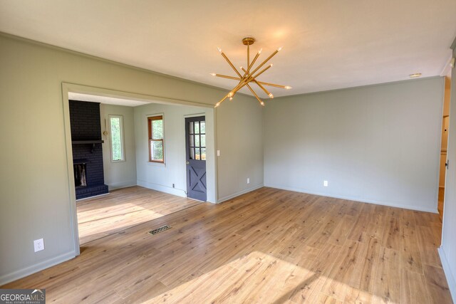 unfurnished room with a chandelier, wood finished floors, baseboards, and visible vents