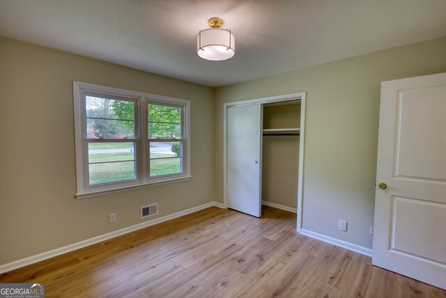 unfurnished bedroom with light wood-style floors, visible vents, baseboards, and a closet