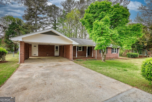 ranch-style home with a front yard, fence, concrete driveway, brick siding, and an attached carport
