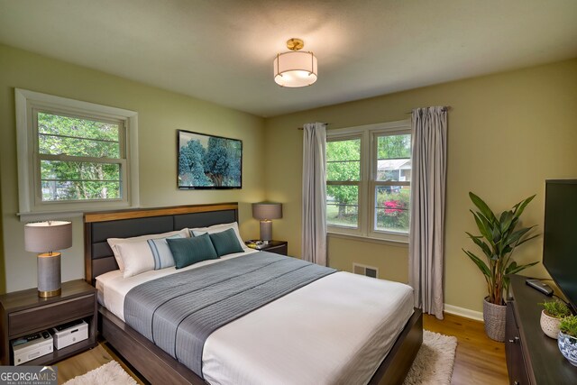 bedroom featuring wood finished floors, baseboards, and visible vents