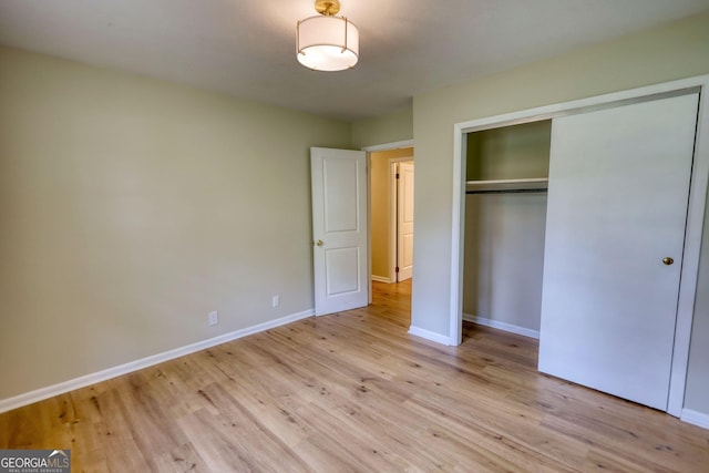 unfurnished bedroom with a closet, baseboards, and light wood finished floors