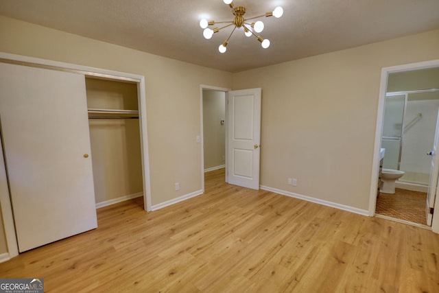 unfurnished bedroom with ensuite bathroom, baseboards, a chandelier, and light wood-style floors