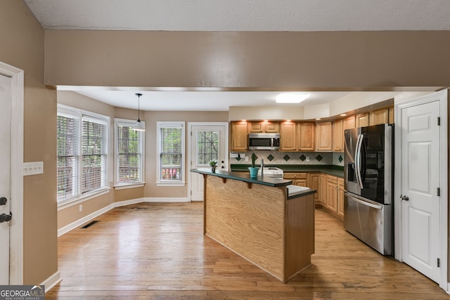 86 S Chattahoochee Dr, Hogansville, GA 30230 - kitchen with stainless steel appliances, dark countertops, light wood-style floors, a kitchen bar, and backsplash