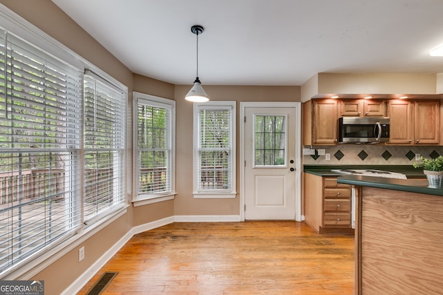 86 S Chattahoochee Dr, Hogansville, GA 30230 - kitchen featuring stainless steel microwave, dark countertops, light wood-type flooring, tasteful backsplash, and hanging light fixtures