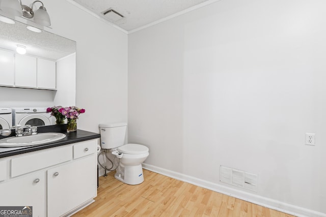 bathroom with crown molding, wood finished floors, visible vents, and independent washer and dryer