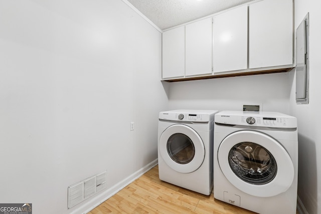 laundry room featuring baseboards, visible vents, light wood-style floors, independent washer and dryer, and cabinet space
