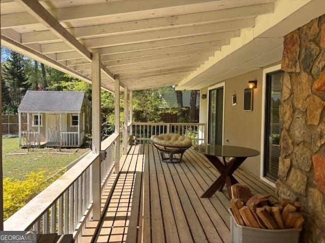 deck featuring a storage shed, an outbuilding, fence, and a lawn