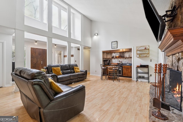 living room featuring a healthy amount of sunlight, a towering ceiling, light wood-style floors, and a fireplace