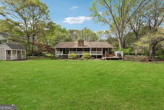 rear view of property featuring an outdoor structure, a lawn, a storage shed, and a deck
