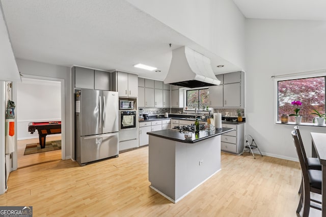 kitchen with gray cabinets, island range hood, dark countertops, and stainless steel appliances