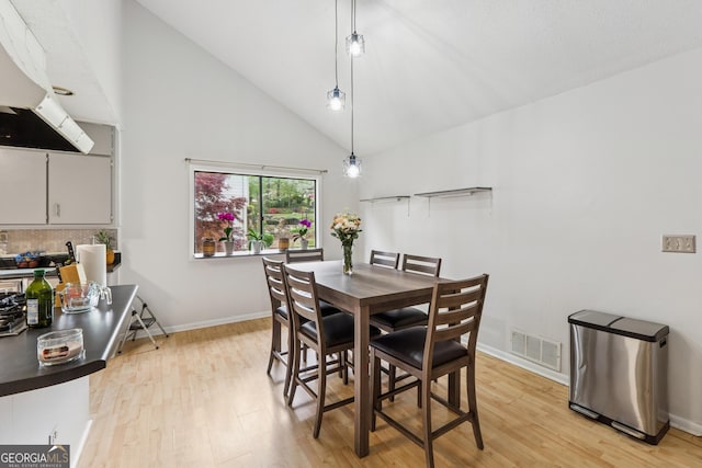 dining area featuring high vaulted ceiling, baseboards, visible vents, and light wood-type flooring