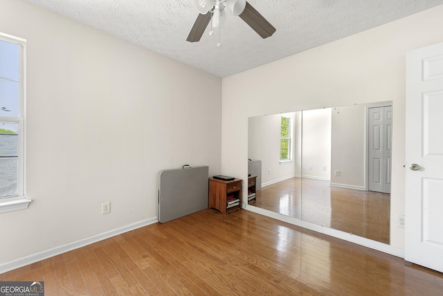 interior space with wood-type flooring, a textured ceiling, and baseboards