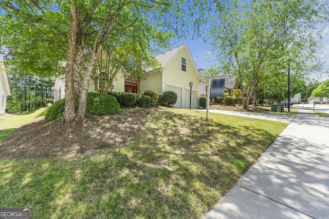 view of property exterior featuring a yard, an attached garage, and driveway