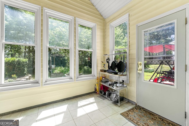 sunroom / solarium with a wealth of natural light, lofted ceiling, and tile patterned flooring