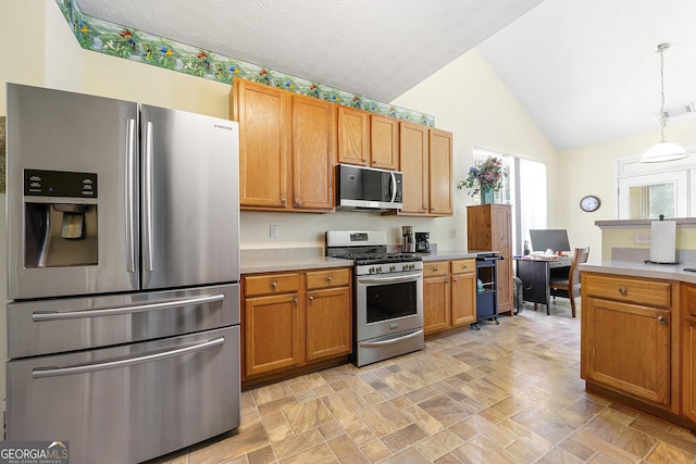 kitchen featuring vaulted ceiling, brown cabinetry, light countertops, decorative light fixtures, and appliances with stainless steel finishes