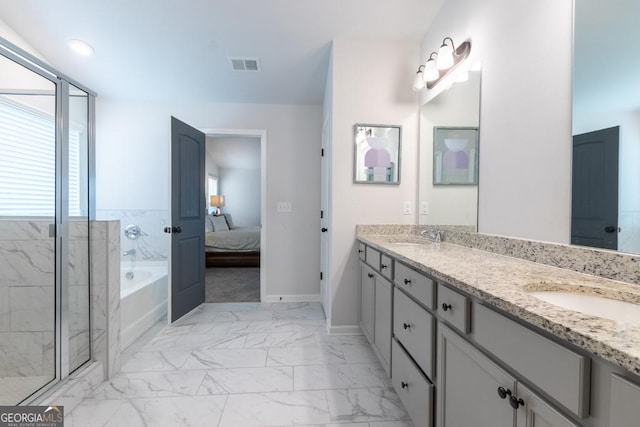 ensuite bathroom featuring double vanity, a bath, visible vents, marble finish floor, and a sink
