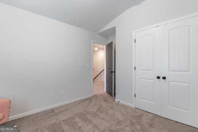 unfurnished bedroom featuring a closet, baseboards, carpet, and vaulted ceiling