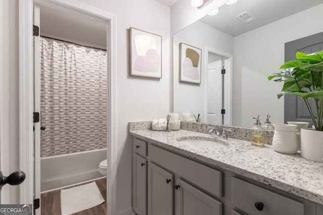 bathroom with vanity, visible vents, toilet, shower / bath combo, and wood finished floors