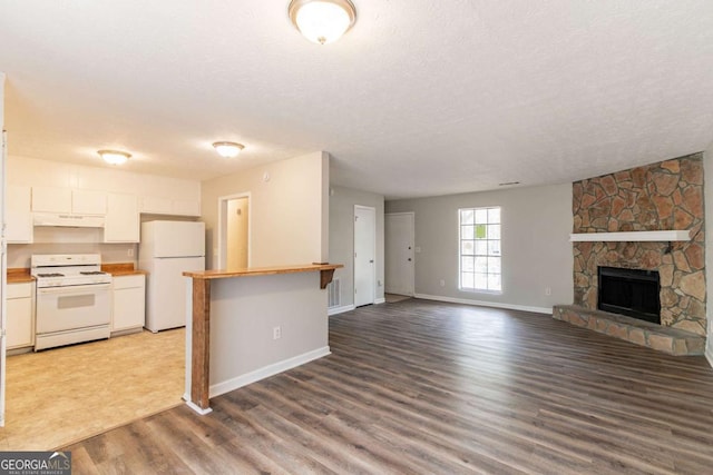 kitchen featuring white appliances, a textured ceiling, white cabinets, under cabinet range hood, and wood finished floors