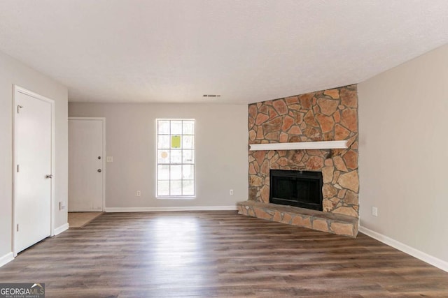 unfurnished living room with a fireplace, visible vents, baseboards, and wood finished floors