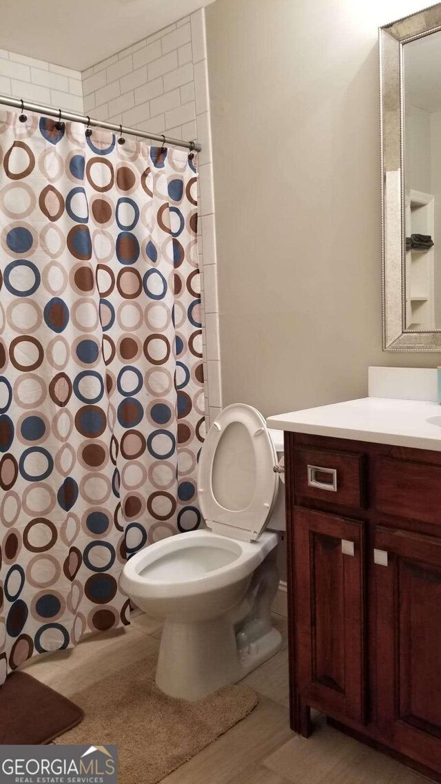 full bath with toilet, curtained shower, and vanity