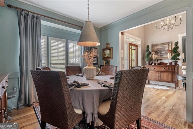 295 Sagamore Cv NW, Sugar Hill, GA 30518 - dining area featuring light wood finished floors, a chandelier, and ornamental molding