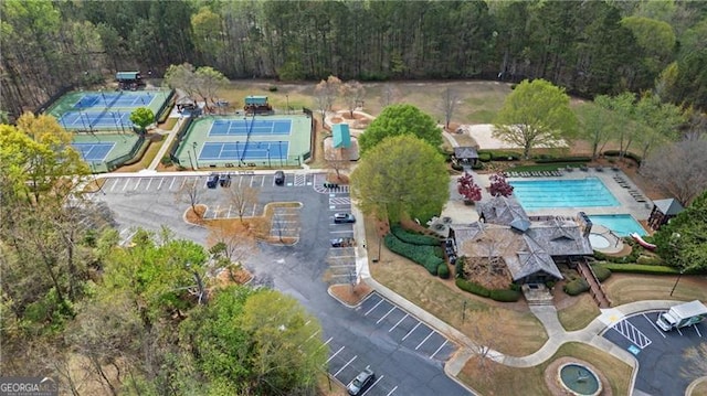 aerial view of property and surrounding area with a pool and a heavily wooded area