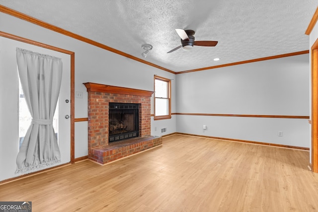 unfurnished living room featuring visible vents, a brick fireplace, ornamental molding, ceiling fan, and wood finished floors