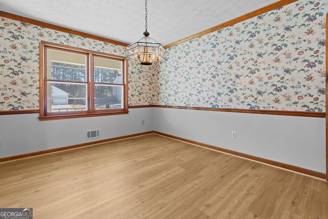 unfurnished room featuring visible vents, a notable chandelier, light wood-style floors, a textured ceiling, and wallpapered walls