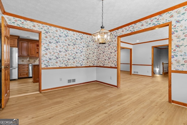 unfurnished dining area with wallpapered walls, ornamental molding, visible vents, wainscoting, and light wood finished floors
