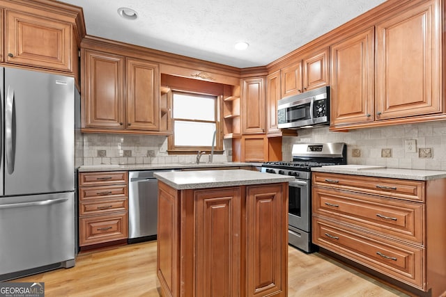 kitchen with light wood-style flooring, brown cabinetry, and appliances with stainless steel finishes