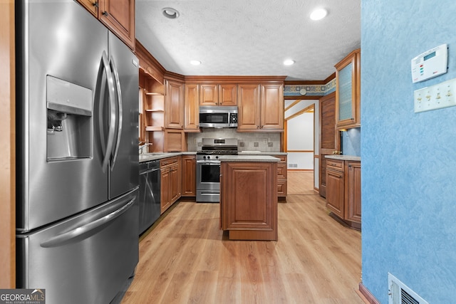 kitchen with light wood-type flooring, a center island, a textured ceiling, open shelves, and stainless steel appliances