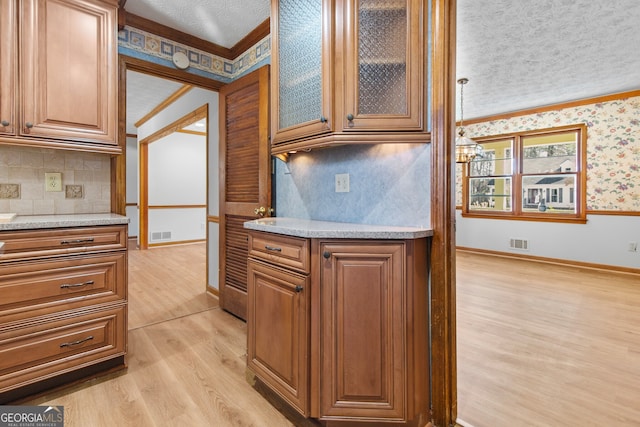 kitchen featuring light wood finished floors, visible vents, a textured ceiling, and wallpapered walls