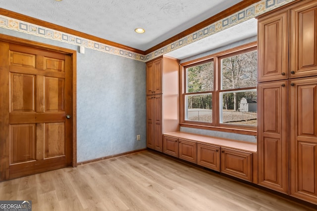 unfurnished bedroom with light wood finished floors, a textured ceiling, and baseboards