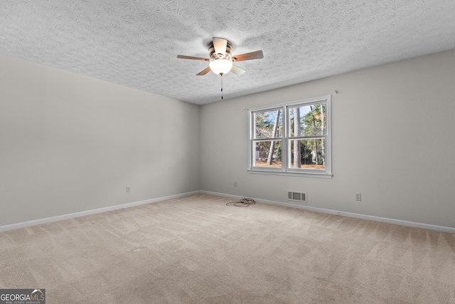 carpeted spare room with visible vents, baseboards, a textured ceiling, and ceiling fan