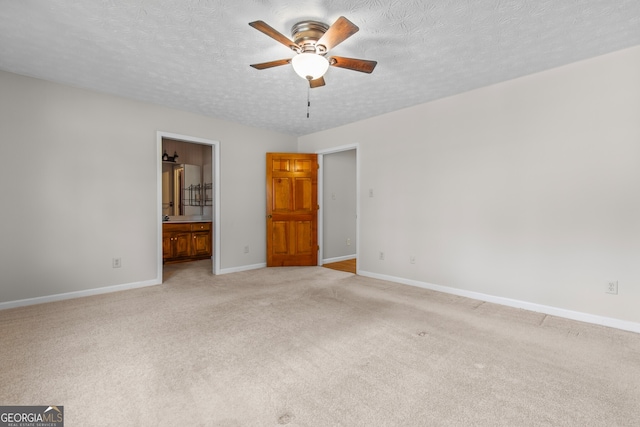 unfurnished bedroom featuring ensuite bathroom, baseboards, light carpet, and a textured ceiling