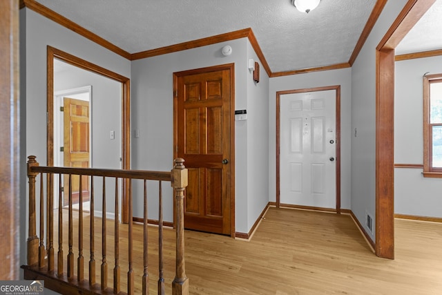 entryway featuring a textured ceiling, light wood finished floors, baseboards, and visible vents