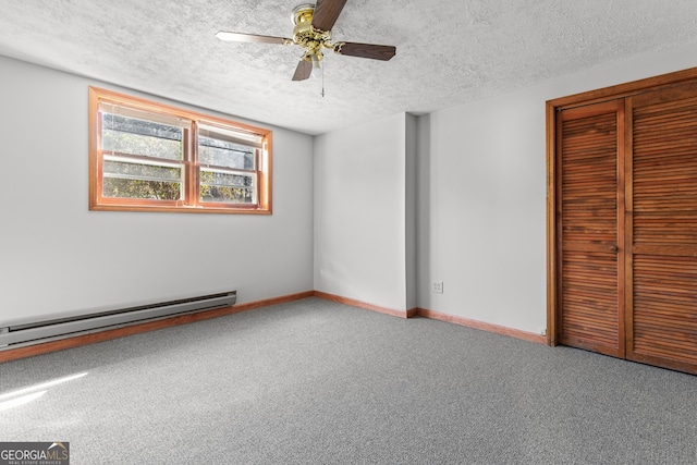 unfurnished bedroom with a textured ceiling, a closet, carpet floors, a baseboard heating unit, and baseboards