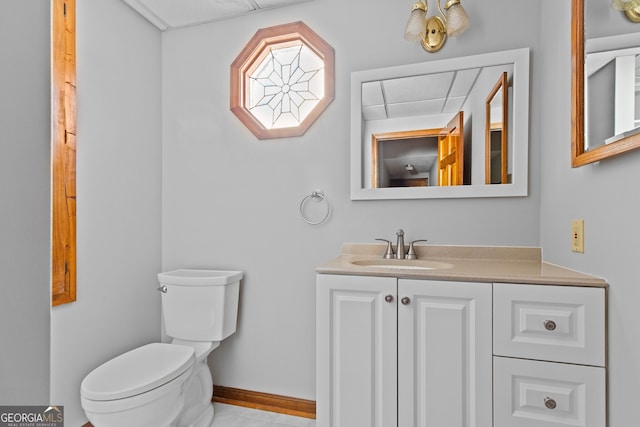 bathroom featuring toilet, vanity, and baseboards