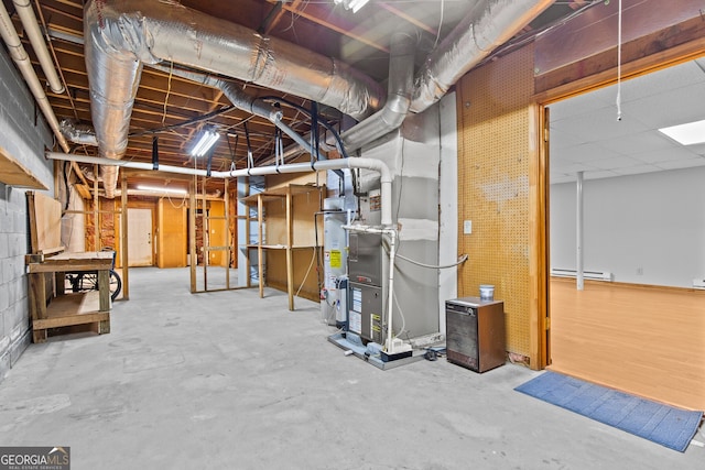 unfinished below grade area with a baseboard radiator and gas water heater