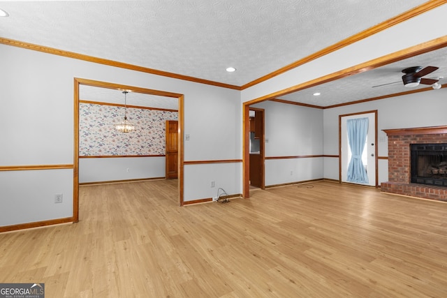 unfurnished living room with a fireplace, light wood-style flooring, a textured ceiling, ornamental molding, and baseboards