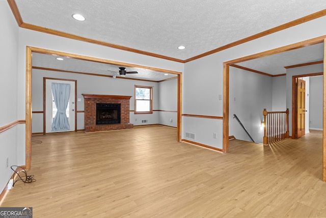 unfurnished living room with visible vents, ceiling fan, a fireplace, a textured ceiling, and light wood finished floors