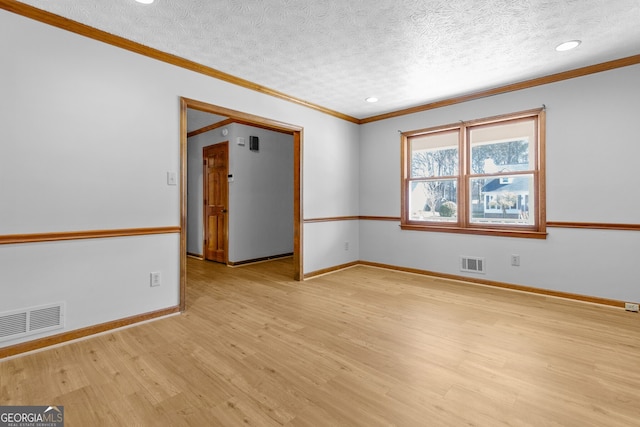 spare room featuring light wood-type flooring, crown molding, and visible vents